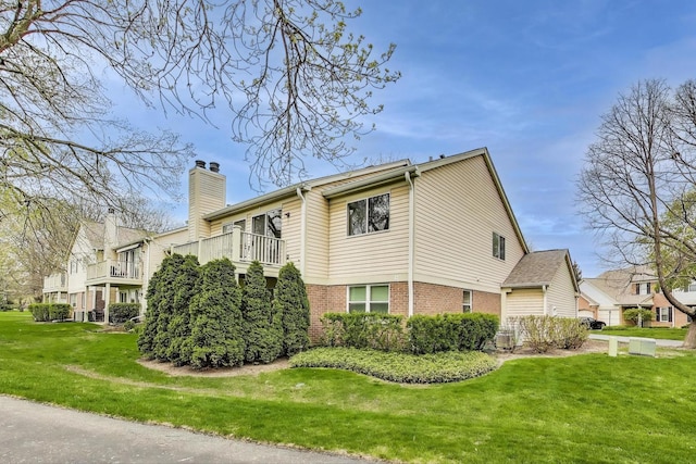 1608 Pennsbury Ct Unit A2, Wheeling, IL 60090 - view of home's exterior with brick siding, a chimney, a yard, and a balcony