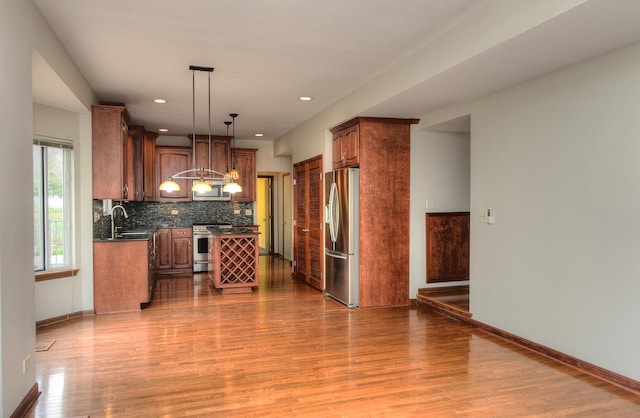 kitchen with decorative backsplash, appliances with stainless steel finishes, wood finished floors, and dark countertops