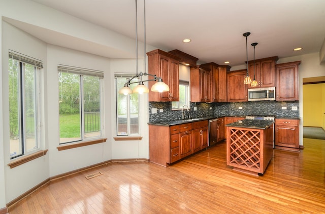 kitchen with a kitchen island, appliances with stainless steel finishes, a healthy amount of sunlight, and light wood finished floors