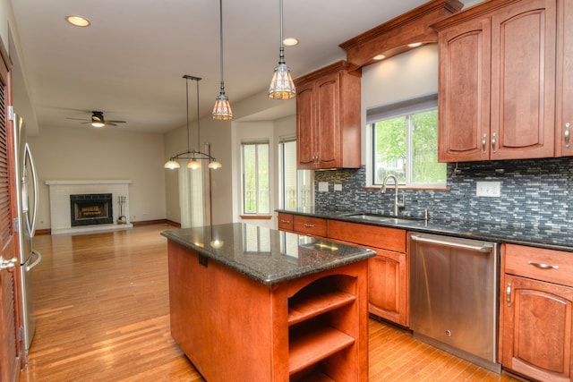 kitchen featuring ceiling fan, a sink, a center island, stainless steel appliances, and tasteful backsplash