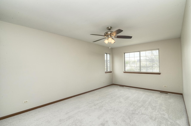 spare room with baseboards, a ceiling fan, visible vents, and light colored carpet