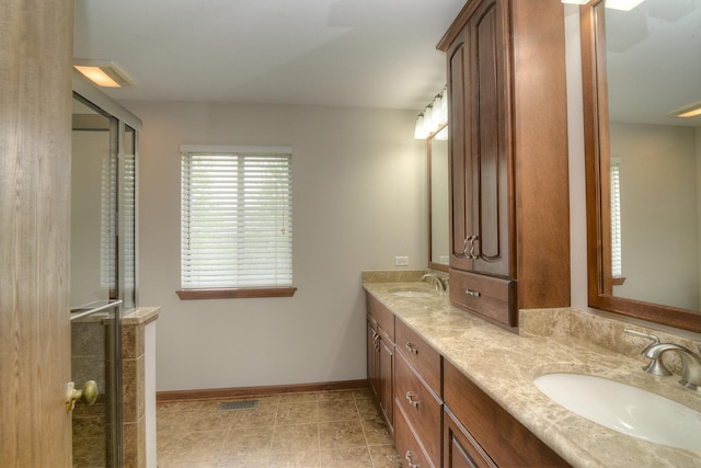 full bath featuring a sink, baseboards, a stall shower, and double vanity