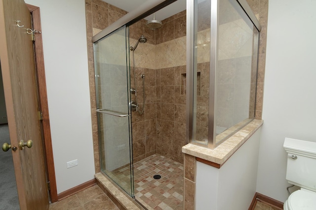 bathroom featuring baseboards, a stall shower, and toilet