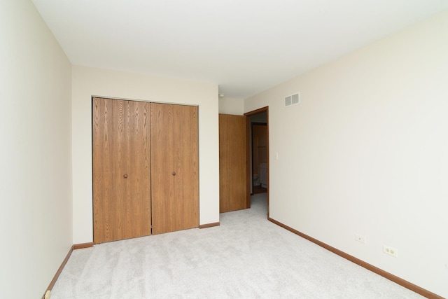 unfurnished bedroom featuring light colored carpet, baseboards, visible vents, and a closet