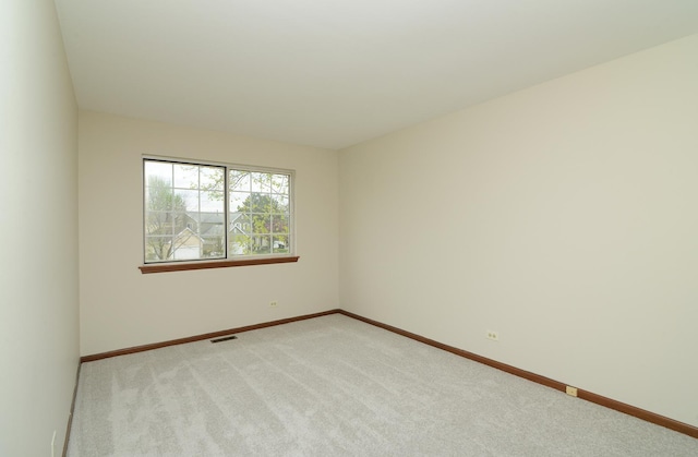 spare room featuring baseboards, visible vents, and light carpet