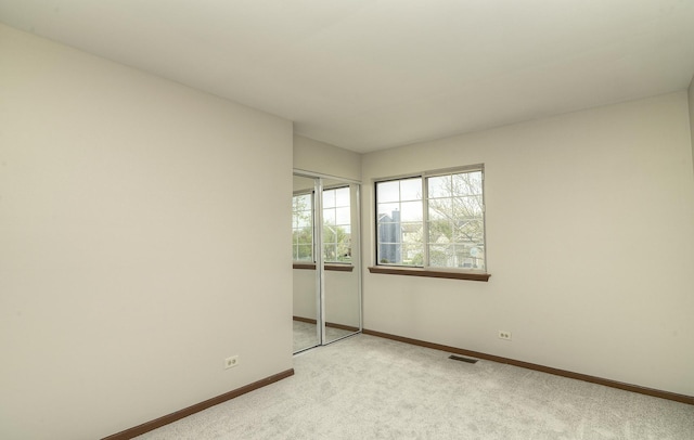 empty room with baseboards, light colored carpet, and visible vents