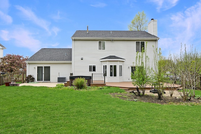 rear view of property with fence, a deck, a chimney, a patio area, and a yard
