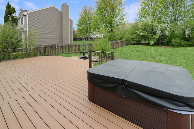 wooden terrace featuring a fenced backyard, a lawn, and a hot tub