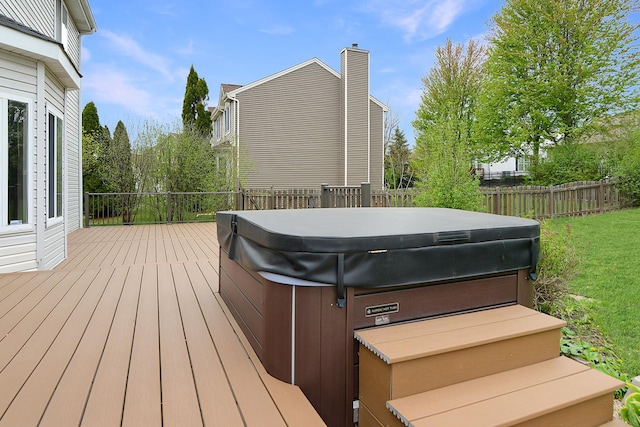 wooden terrace featuring a hot tub, a lawn, and fence