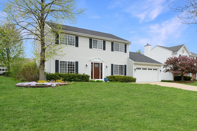 colonial house with an attached garage, a chimney, driveway, and a front yard