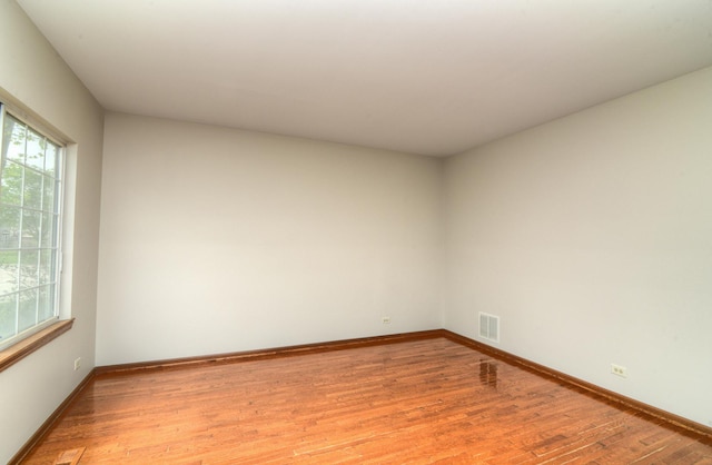 unfurnished room featuring baseboards, visible vents, and light wood-style flooring