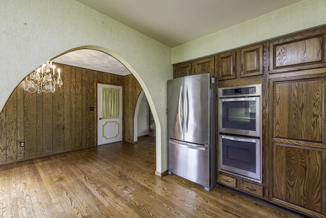 301 Garnett Ave, Winthrop Harbor, IL 60096 - kitchen featuring stainless steel appliances, wood finished floors, arched walkways, and a chandelier