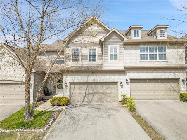 multi unit property featuring concrete driveway, brick siding, and a garage