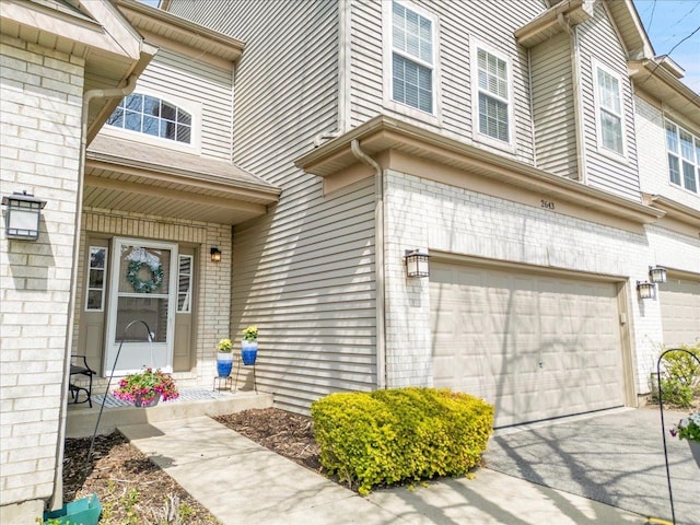 entrance to property featuring an attached garage and brick siding