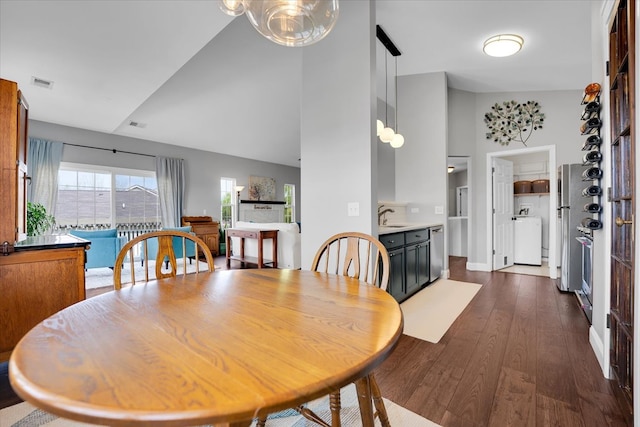 dining area with high vaulted ceiling, visible vents, washer / dryer, and dark wood-type flooring