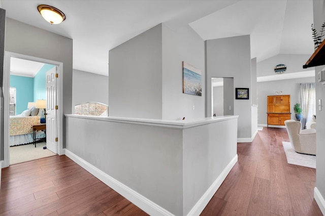 hall with baseboards, vaulted ceiling, and hardwood / wood-style flooring