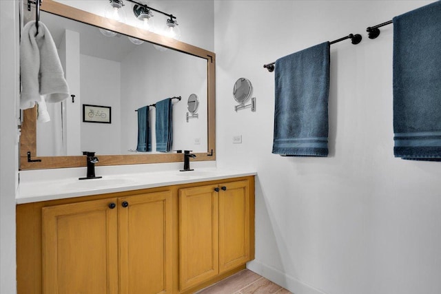 full bathroom with double vanity, baseboards, and a sink