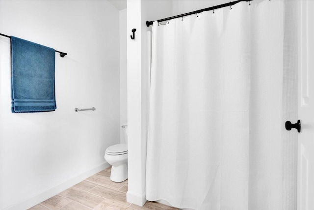 bathroom featuring wood tiled floor, toilet, and a shower with curtain