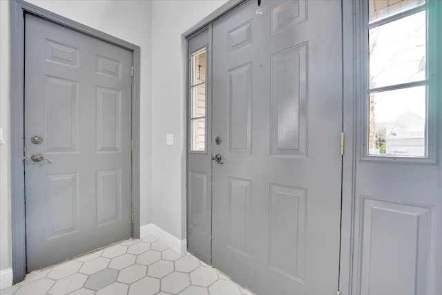 foyer with baseboards, light tile patterned flooring, and a healthy amount of sunlight