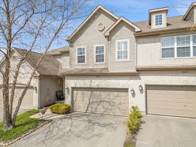 view of property featuring brick siding, an attached garage, and driveway