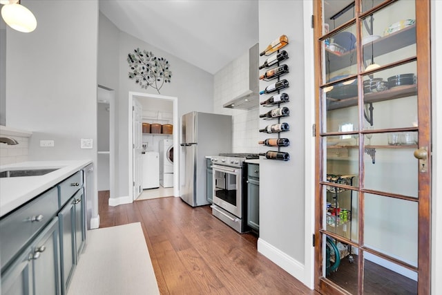 kitchen with dark wood-type flooring, tasteful backsplash, a sink, independent washer and dryer, and stainless steel appliances