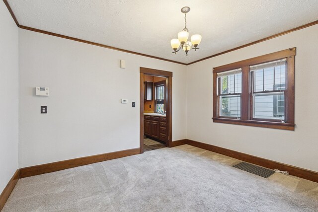2228 8th St, Rockford, IL 61104 - unfurnished room featuring crown molding, light colored carpet, a notable chandelier, baseboards, and visible vents