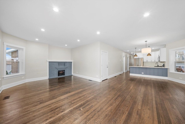 4825 W Oakdale Ave, Chicago, IL 60641 - unfurnished living room with recessed lighting, dark wood finished floors, baseboards, a fireplace, and a sink