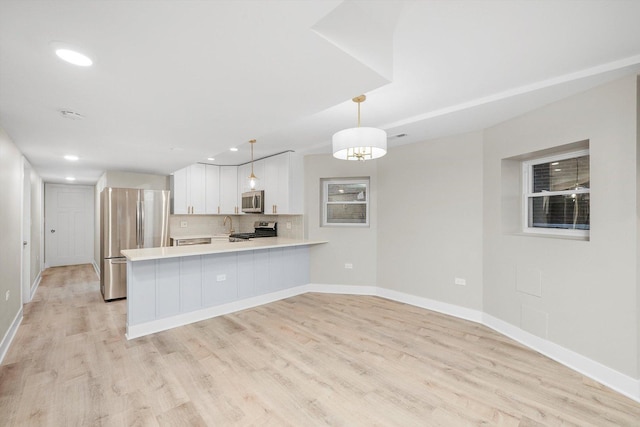 4825 W Oakdale Ave, Chicago, IL 60641 - kitchen with stainless steel appliances, light countertops, a peninsula, white cabinetry, and light wood finished floors