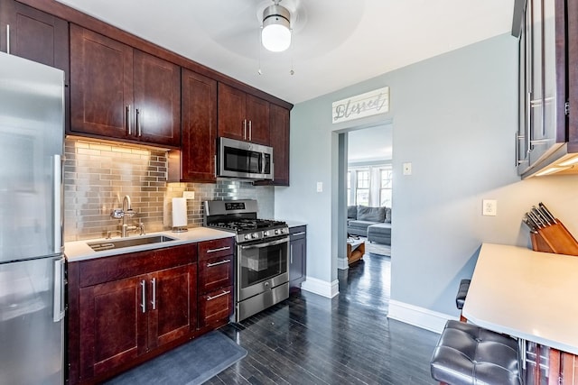 kitchen with a ceiling fan, dark wood-style floors, a sink, backsplash, and stainless steel appliances