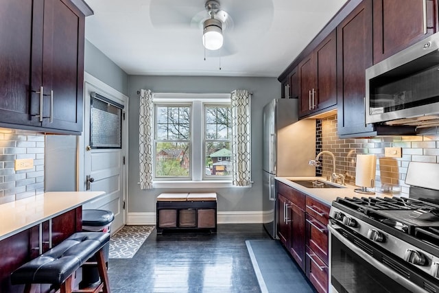 kitchen with a ceiling fan, light countertops, baseboards, a sink, and stainless steel appliances