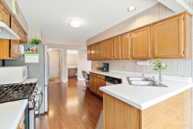 kitchen with dark wood finished floors, a sink, light countertops, wallpapered walls, and white appliances