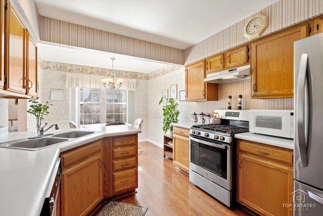 kitchen featuring appliances with stainless steel finishes, under cabinet range hood, and wallpapered walls