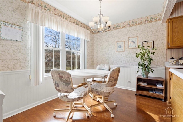dining area featuring wallpapered walls, wood finished floors, a chandelier, and a wainscoted wall