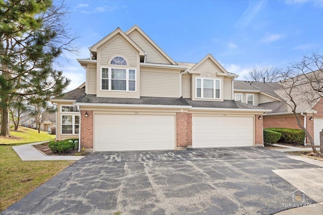 view of front of house with a garage, brick siding, and aphalt driveway