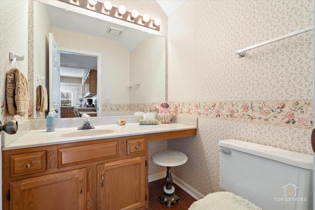 bathroom with toilet, wallpapered walls, visible vents, and vanity