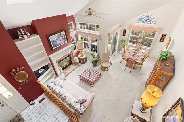 carpeted living room with a ceiling fan, high vaulted ceiling, and a glass covered fireplace