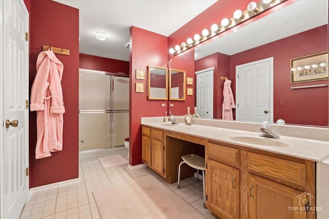 full bath featuring double vanity, a stall shower, a sink, baseboards, and toilet