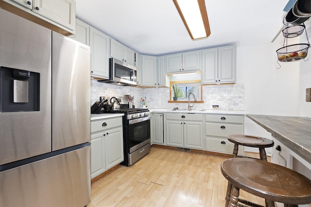 14958 Kildare Ave, Midlothian, IL 60445 - kitchen with stainless steel appliances, a sink, light wood-style flooring, backsplash, and light countertops