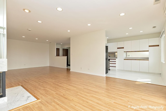 unfurnished living room with light wood-type flooring, recessed lighting, and visible vents