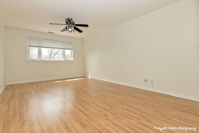 spare room featuring baseboards, visible vents, ceiling fan, and light wood finished floors