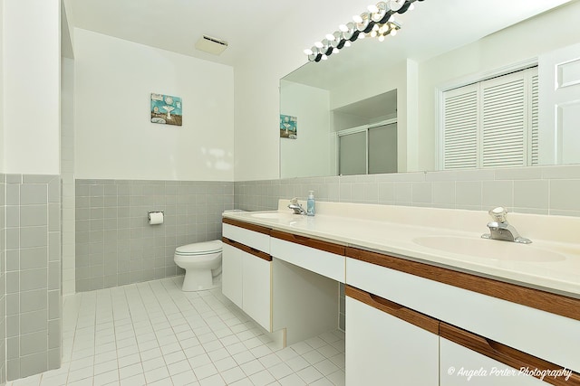 full bath with a sink, tile patterned flooring, a shower stall, and toilet