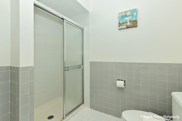 full bathroom featuring a stall shower, toilet, and tile walls