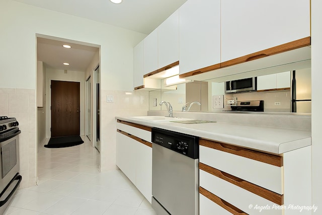 kitchen featuring light countertops, tile walls, appliances with stainless steel finishes, and white cabinetry