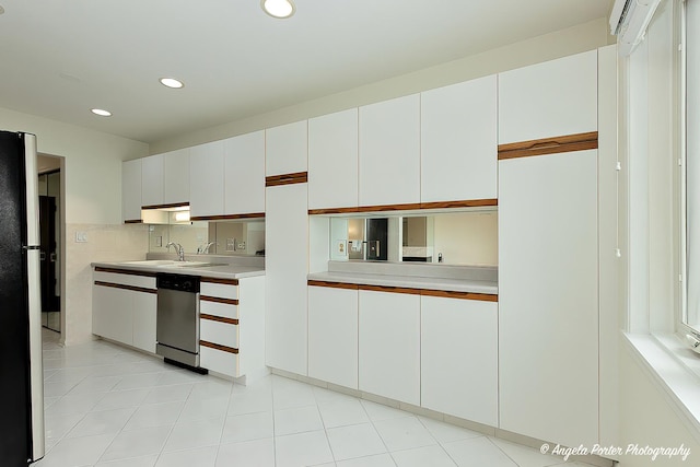 kitchen featuring stainless steel dishwasher, light countertops, a sink, white cabinets, and recessed lighting