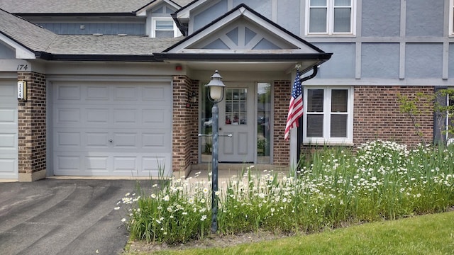 174 Grove Ave Unit B, Des Plaines, IL 60016 - view of front facade featuring brick siding, driveway, an attached garage, stucco siding, and a shingled roof