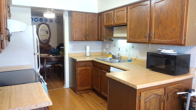 kitchen featuring electric range, light countertops, brown cabinetry, tasteful backsplash, and under cabinet range hood