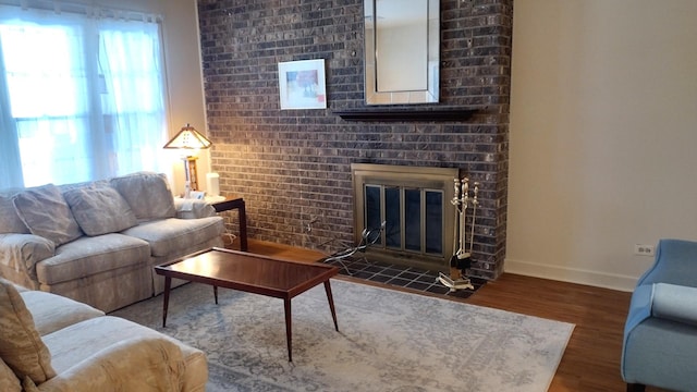 living area featuring baseboards, a fireplace, and wood finished floors