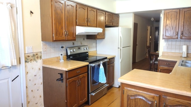 174 Grove Ave Unit B, Des Plaines, IL 60016 - kitchen featuring stainless steel electric range oven, under cabinet range hood, light countertops, brown cabinets, and decorative backsplash