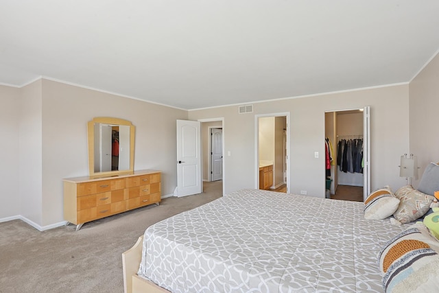 bedroom with light colored carpet, a walk in closet, crown molding, a closet, and baseboards