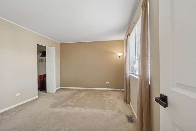 unfurnished bedroom featuring carpet, multiple windows, baseboards, a closet, and ornamental molding